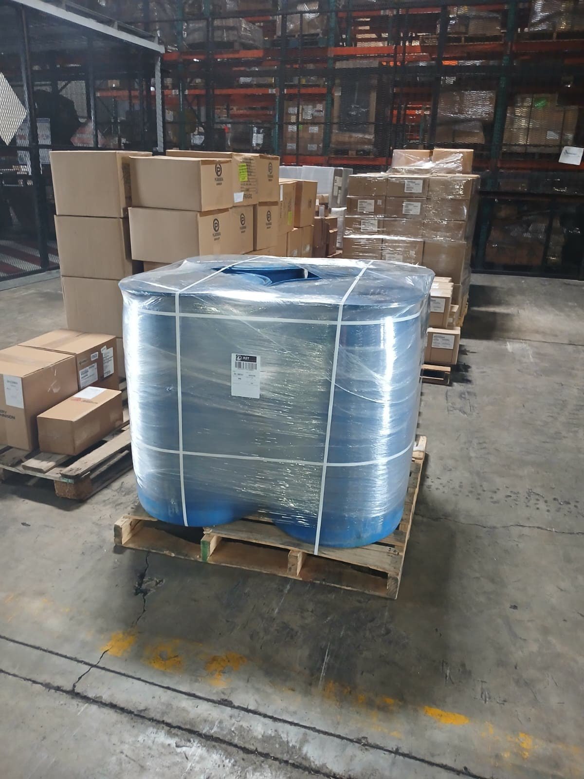 Wrapped pallet of blue batana oil barrels in a warehouse