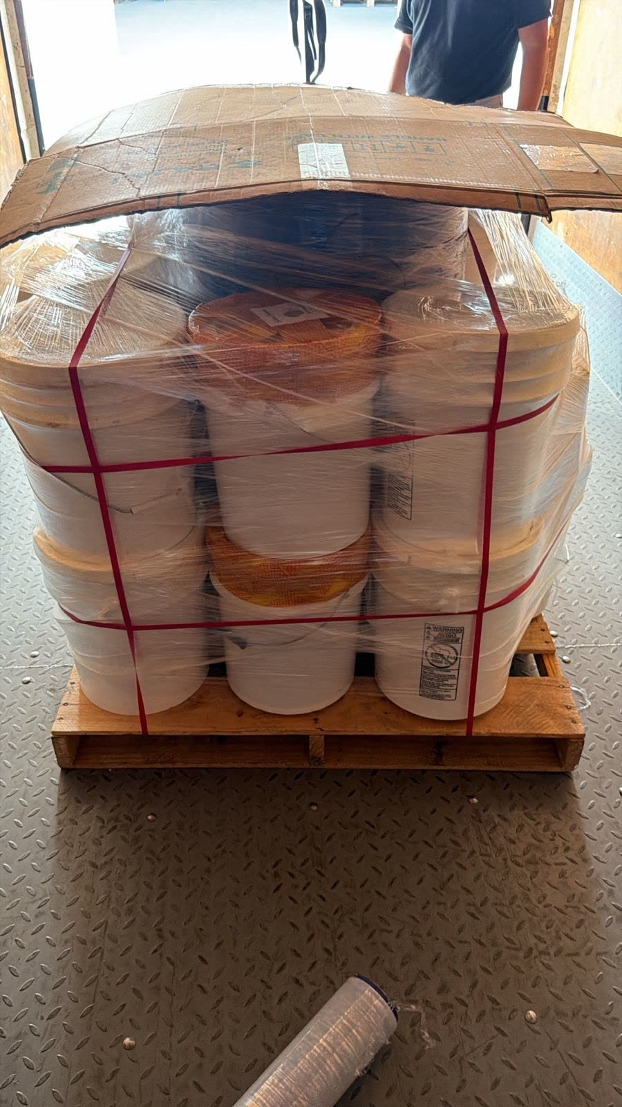 Palletized and strapped 5-gallon buckets of raw batana oil ready for export
